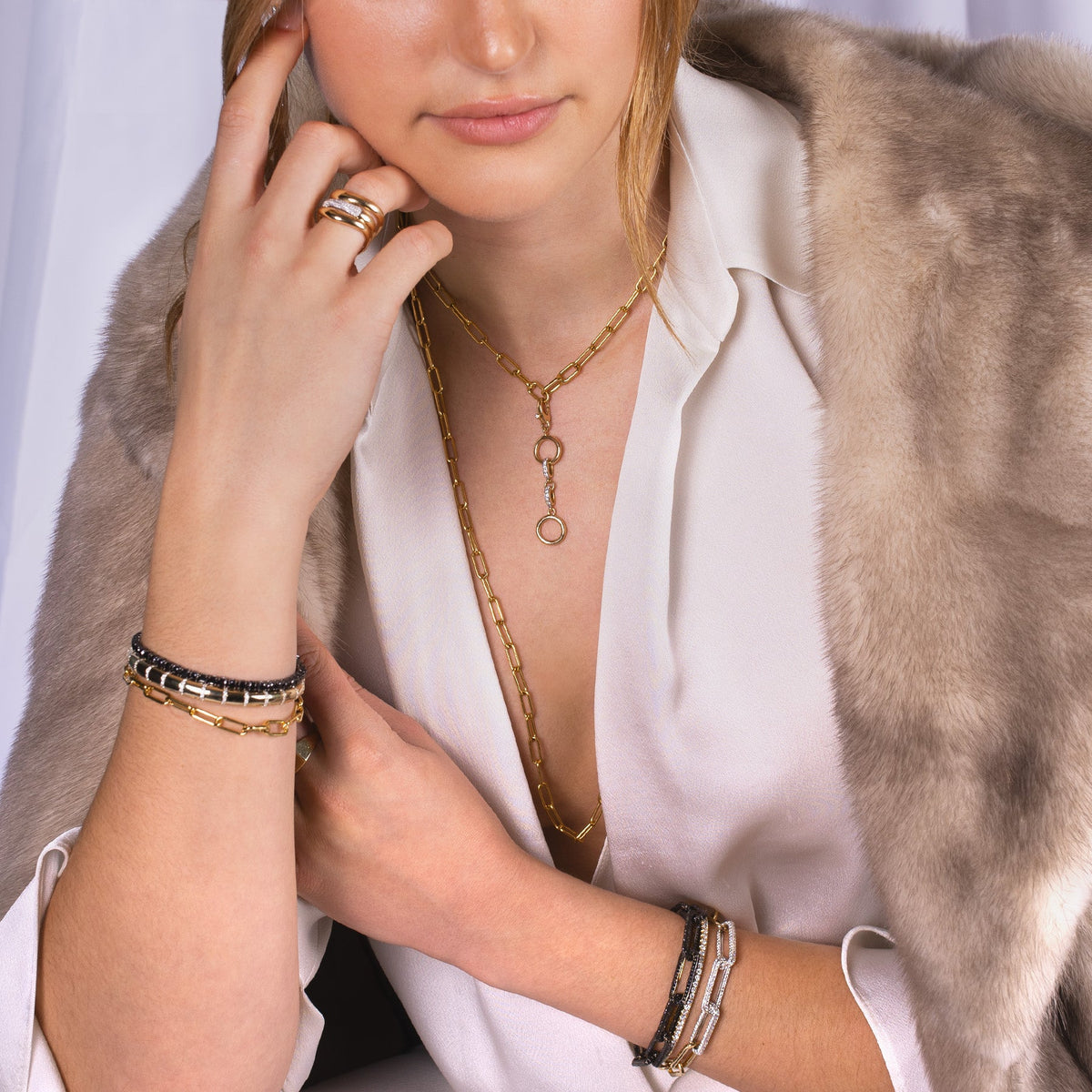 Close-up of a person wearing the 3mm Diamond Stretch Tennis Bracelet, the Black Diamond Infinity Bracelet, the Infinity Diamond Link Bracelet, the Timeless Choker, Forever Ring, Timeless Lariat, and the Diamond Multi-Link Charm Clasp. 