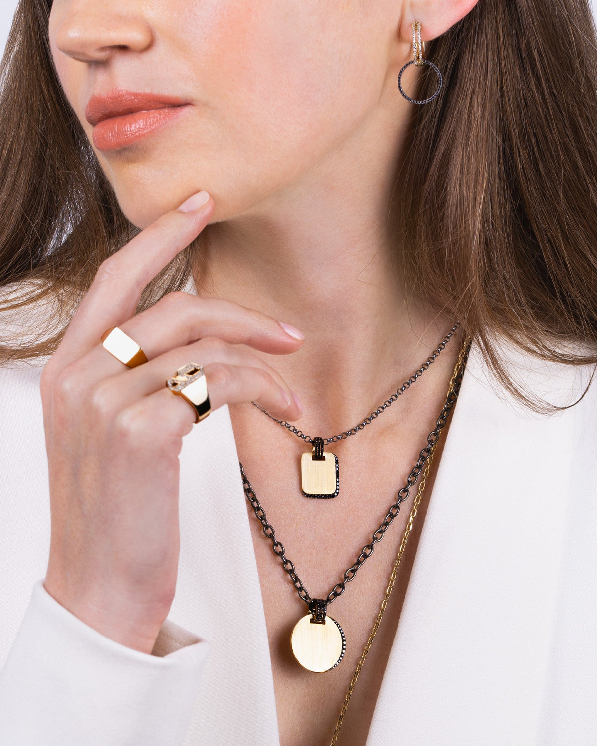 Woman wearing the Black Diamond Eclipse Necklace, the Black Diamond Shadow Necklace, and the Open Bar Huggies with the reversible black diamond side extension