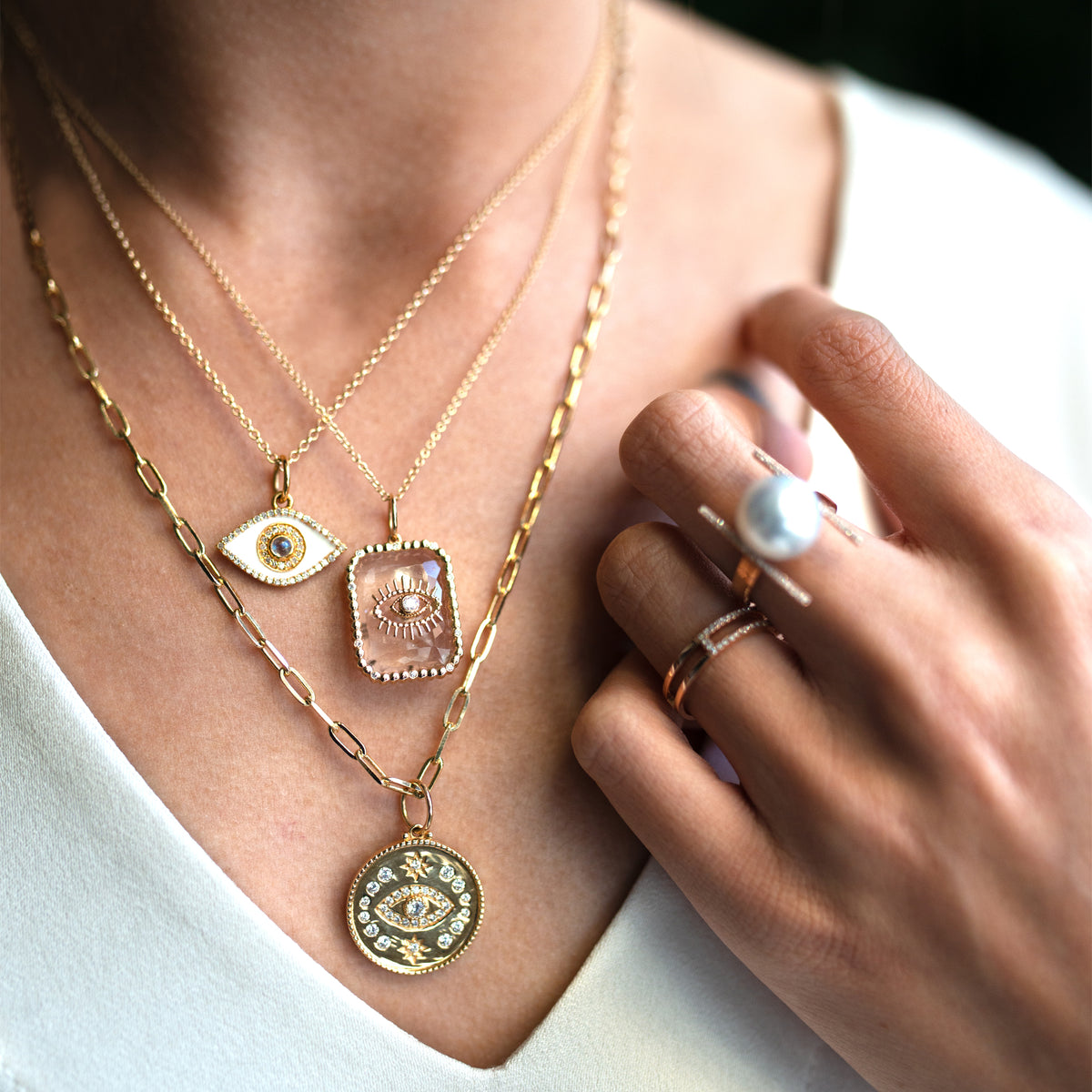 Close up of woman wearing Crystal Evil Eye Necklace, Glam Evil Eye Medallion Necklace, and the Small Enamel Evil Eye Necklace