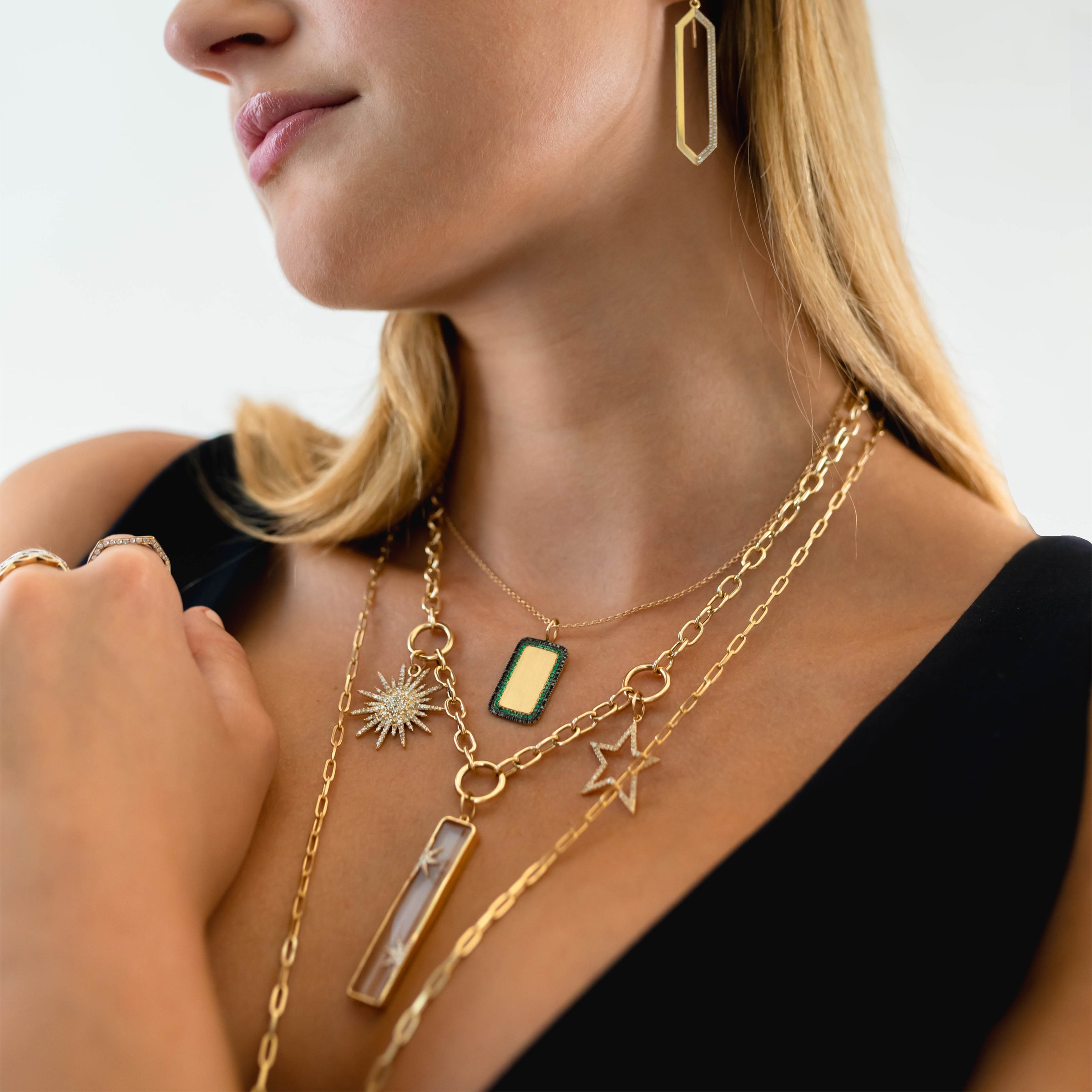Woman wearing Deco Dog Tag Necklace, the Kylie Chain Necklace with the Hollow Diamond Star Pendant, the Starry Night Pendant, and the Sunburst Diamond Penant