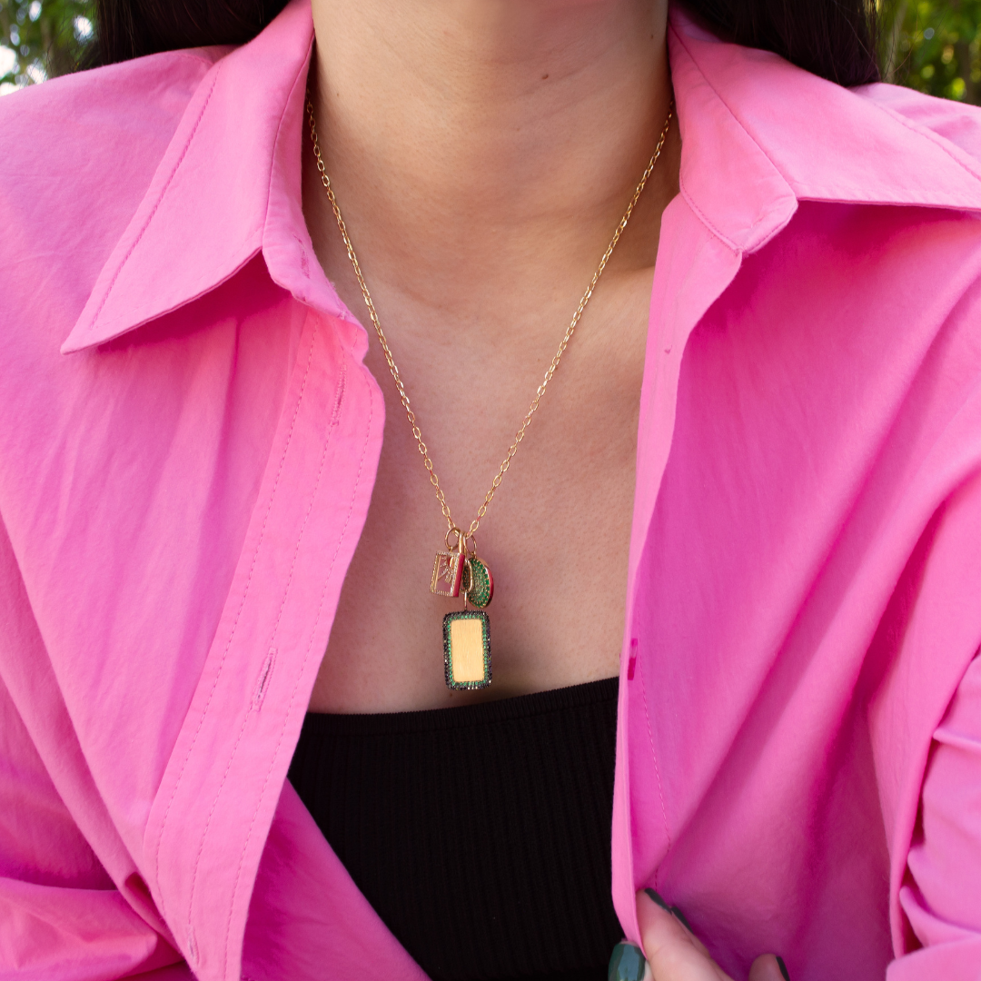 woman wearing a charm necklace with the Deco Dog Tag, the Emerald Ombre Round Pendant, and the Mother-of-Pearl Another Dawn Pendant