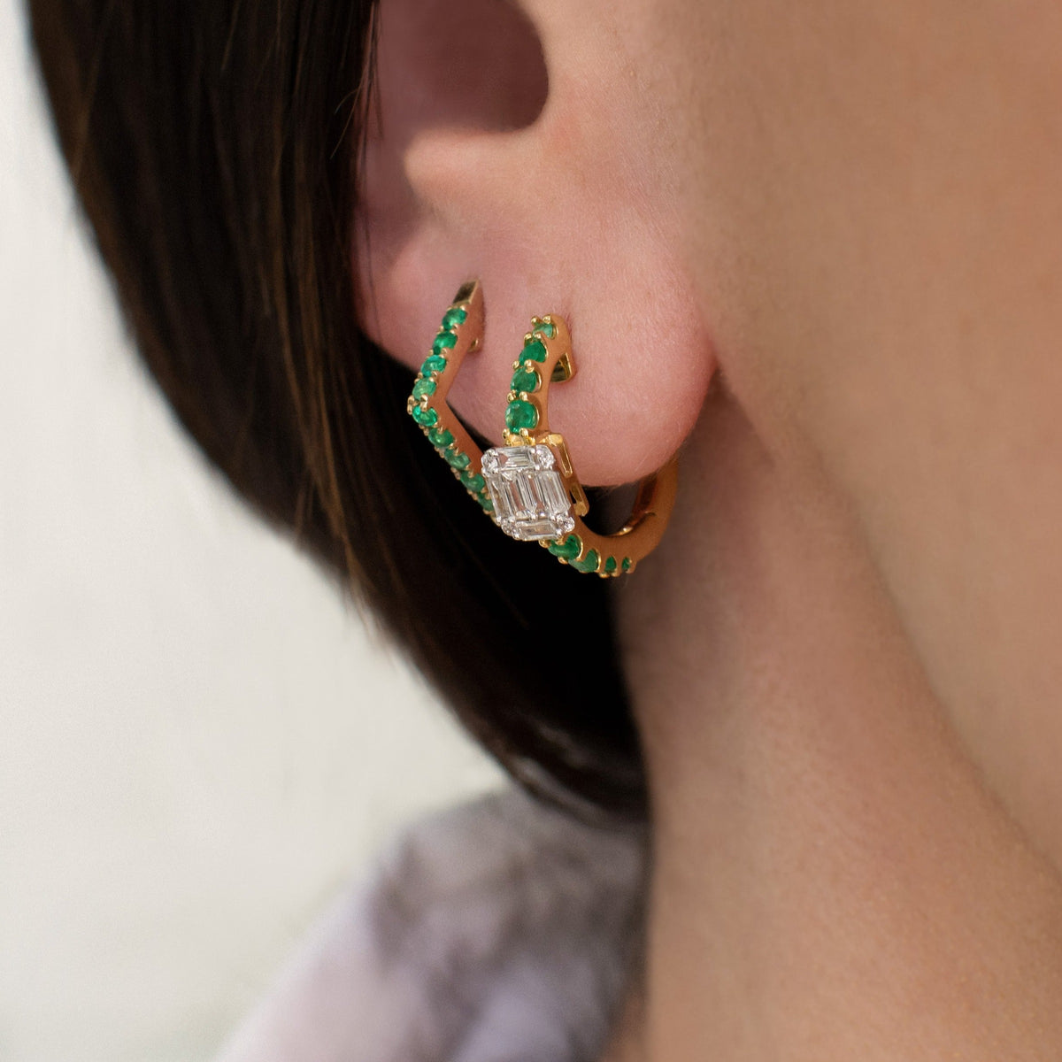 Close up of ear wearing the Deco Emerald Huggies and the Emerald Angular Huggies