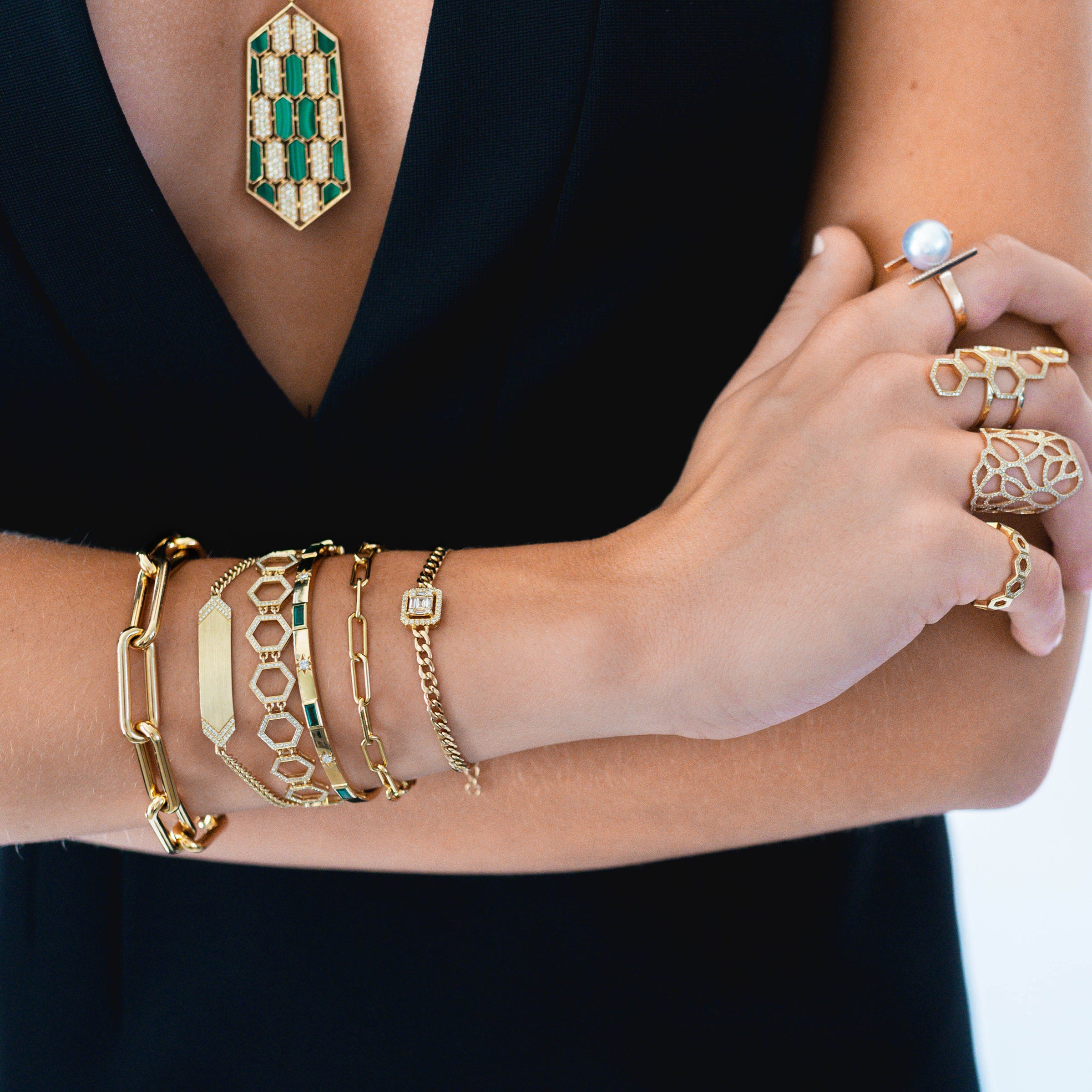 Close up of arm wearing the Diamond Arrow ID Bracelet, the Emerald Baguette & Diamond Bangle, the Timeless Bracelet, the Prism Tennis Bracelet, and the Halo Illusion Bracelet