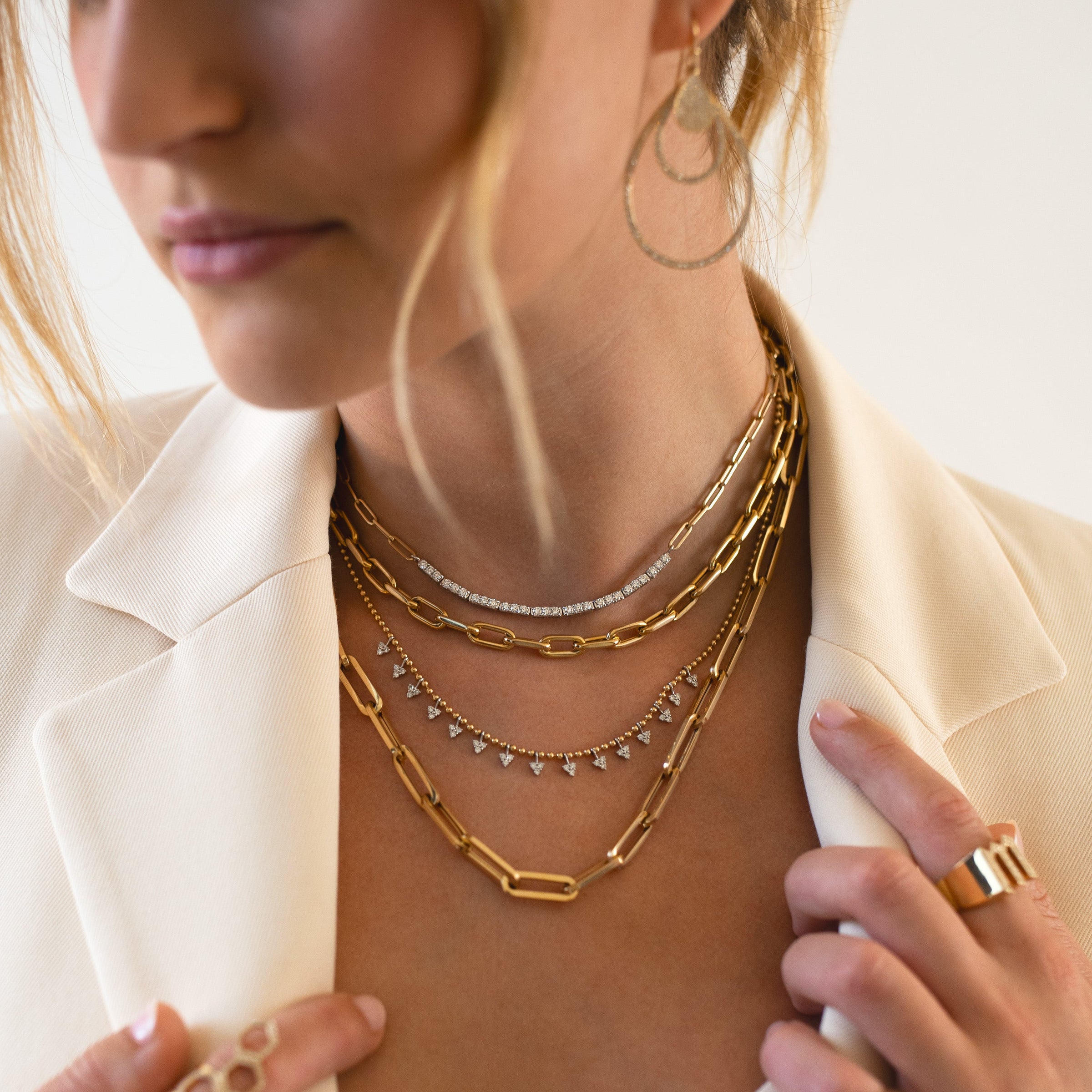 Close up of woman wearing the Diamond Row Necklace, the Barbara Necklace, the Diamond Petal Necklace, and the Paperchain Chain