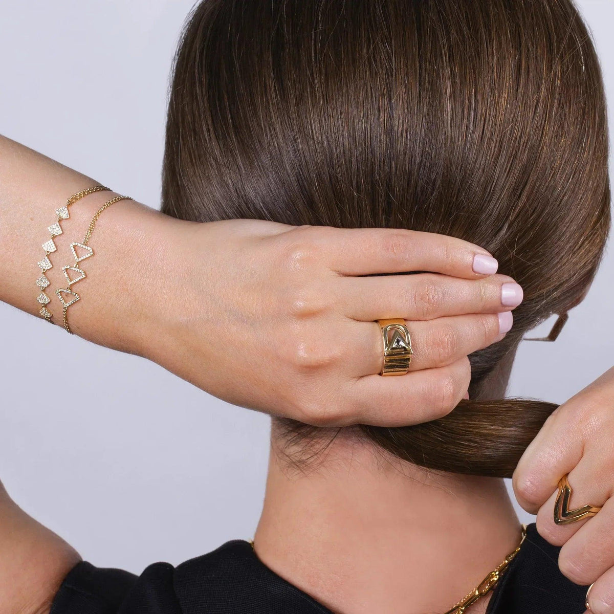 The Back of women and she is wearing the Double Chevron Ring, the Diamond Chevron Ring, the 2mm Diamond Stretch Tennis Bracelet, the Diamond Arrow Id Bracelet, the Trillion Cigar Ring, the Open Shield bracelet, and the Shield Bracelet