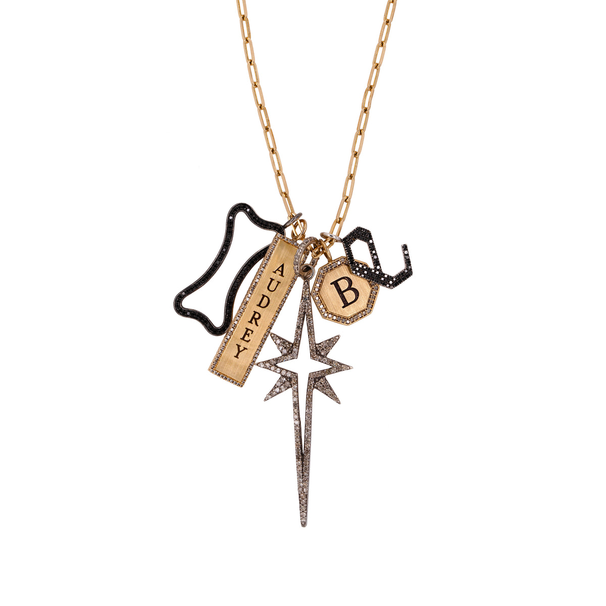 A 14K gold charm necklace with a long link chain and five charms: Engraved "B" Octagon Diamond Pendant, Engraved "Audrey" Double-Sided Dog Tag Pendant w/ White Diamonds, Large Starburst Spear, Large Hollow Black Diamond Dog Bone, Large Black Diamond Alphabet Pendant 