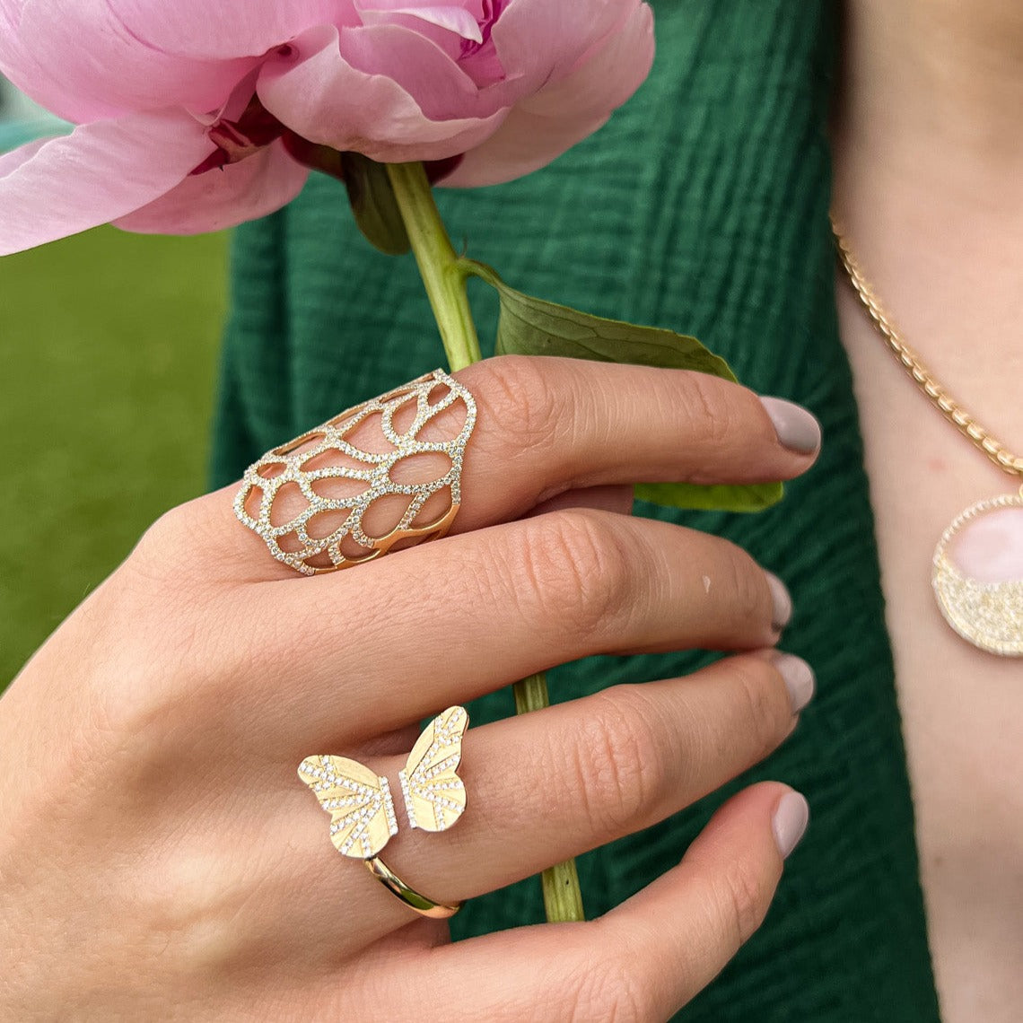 hand holding flower while wearing the Flora Ring, and the Butterfly Ring
