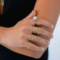 woman wearing the Flora Ring, the full stack of the Prism Stackable Rings, the Pearl with Diamond Bars Ring, and the Queen Bee Ring