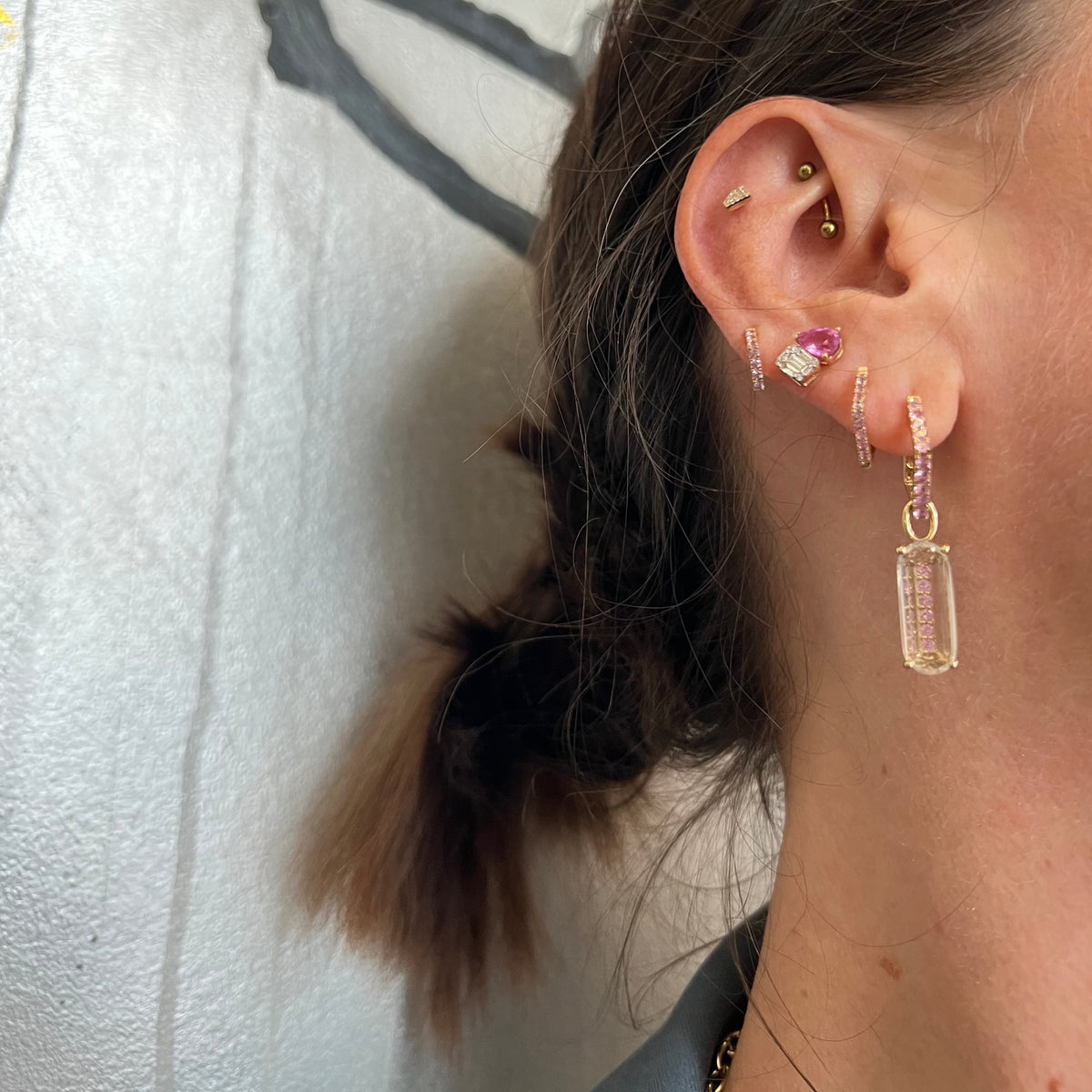 Woman wearing the Illusion Diamond & Pink Sapphire Studs, the Pink Sapphire Angular Studs, the Large Pink Sapphire Angular Studs & Deco Pink Sapphire  Earring Charm