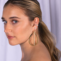 Close-up of a woman wearing Illusion Oval Studs, Baguette Diamond Ear Cuff, and Large Stackable Teardrops & Diamond Stick Earrings