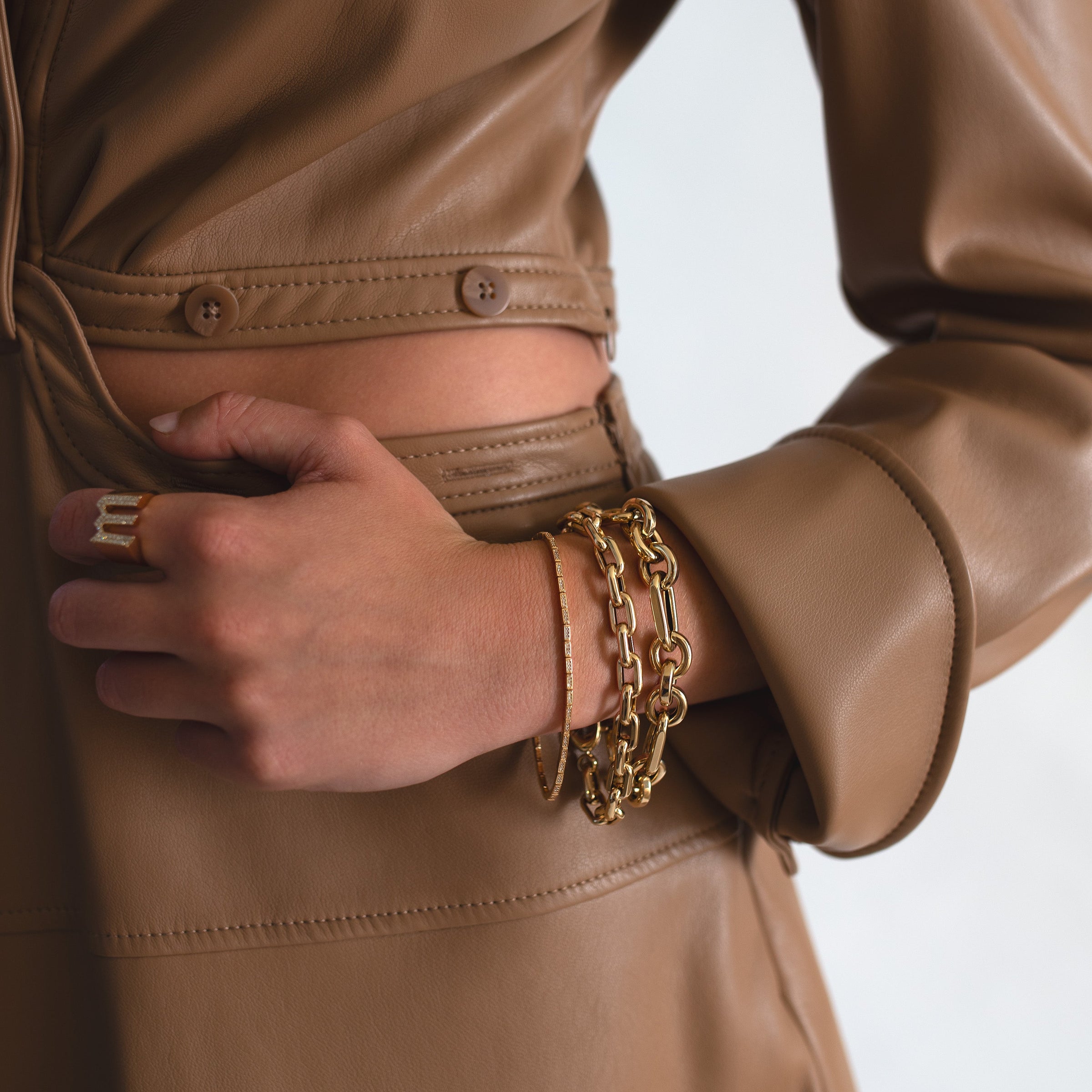 Close-up of a person wearing a brown leather jacket with the Jumbo Mixed-Link Bracelet, and the Diamond Serpent Bracelet