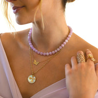 Woman wearing the Kunzite Necklace, the Butterfly Necklace, the Floral and Large Mother-of-pearl Medallion Charm Necklace