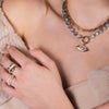 Close-up of a person wearing the Luxe Open Bar Diamond Ring, the Forever Ring, the Floral Evil Eye Eagle Eye Necklace