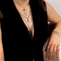 Person wearing "c" Large Black Diamond Alphabet Necklace, the Small Black Diamond Starburst Necklace, and Black Diamond Evil Eye Necklace