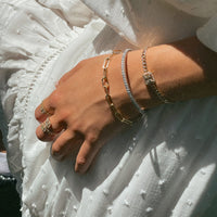 Close up of an arm wearing the 2mm Diamond Stretch Bracelet, the Timeless Bracelet, and the Halo Illusion Bracelet