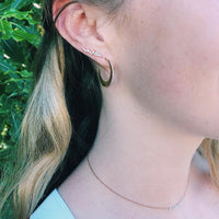 A woman is wearing the Baby Diamond Moon Hoops and the Diamond Cluster Studs