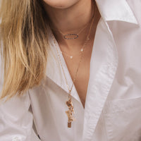 woman is wearing the Black Diamond side of Reversible Diamond Oval Necklace, the Shield Necklace, and a Charm Necklace