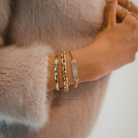 Close up of arm wearing the Diamond Arrow ID Bracelet, the Granada Bracelet, and the Emerald Baguette & Diamond Bangle