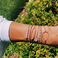 Arm wearing the Diamond Oval Bracelet, the Serpent Diamond  Bracelet, the 7-Dot Diamond Bracelet, the Open Bar Diamond Bracelet, the Long Pearl Bracelet, the Mini Pave Diamond Teardrop Bracelet, and the Diamond Teardrop Bracelet