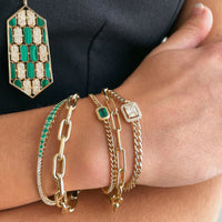 Close up of arm wearing the Emerald Bracelet, the Eternity Bracelet, the Timeless Bracelet, the Emerald Diamond Flexible Bangle, and the Halo Illusion Bracelet