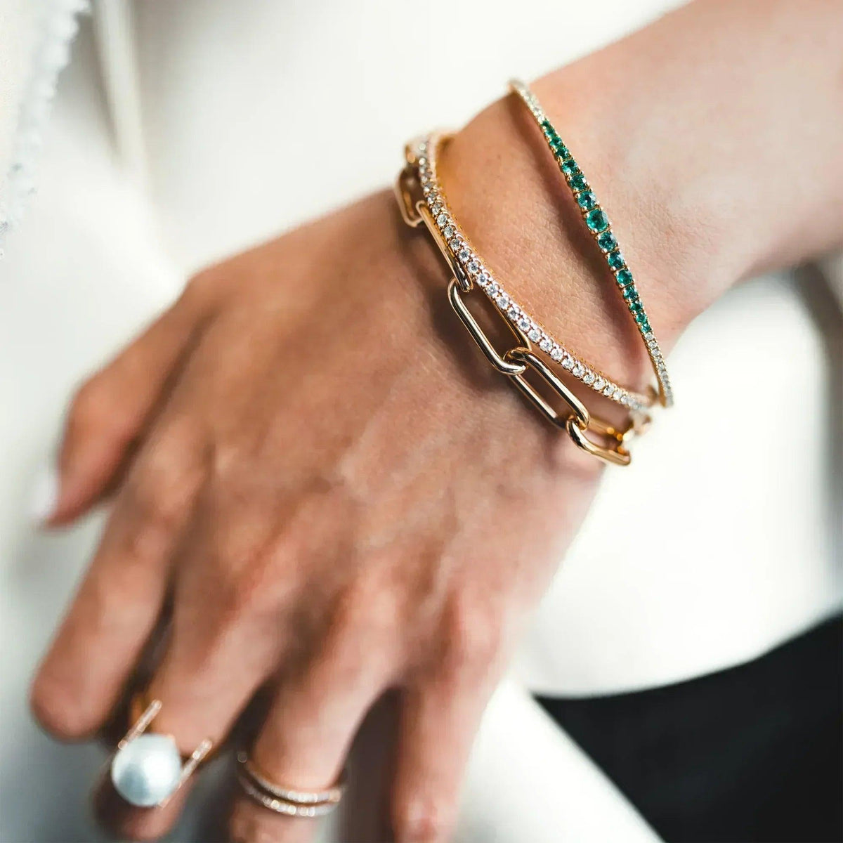 Close up of the arm wearing the Emerald & Diamond Flexible Bangle, the 2mm Diamond Stretch Bracelet