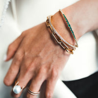 Close up of the arm wearing the Emerald & Diamond Flexible Bangle, the 2mm Diamond Stretch Bracelet