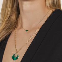 Close-up of a person wearing the Emerald Necklace, the Starburst Diamond & Large Malachite Medallion Necklace