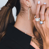 Side profile of woman wearing the Enamel Cigar Ring, thePearl with Diamond Bar Ring, and the Mirror Image Earring