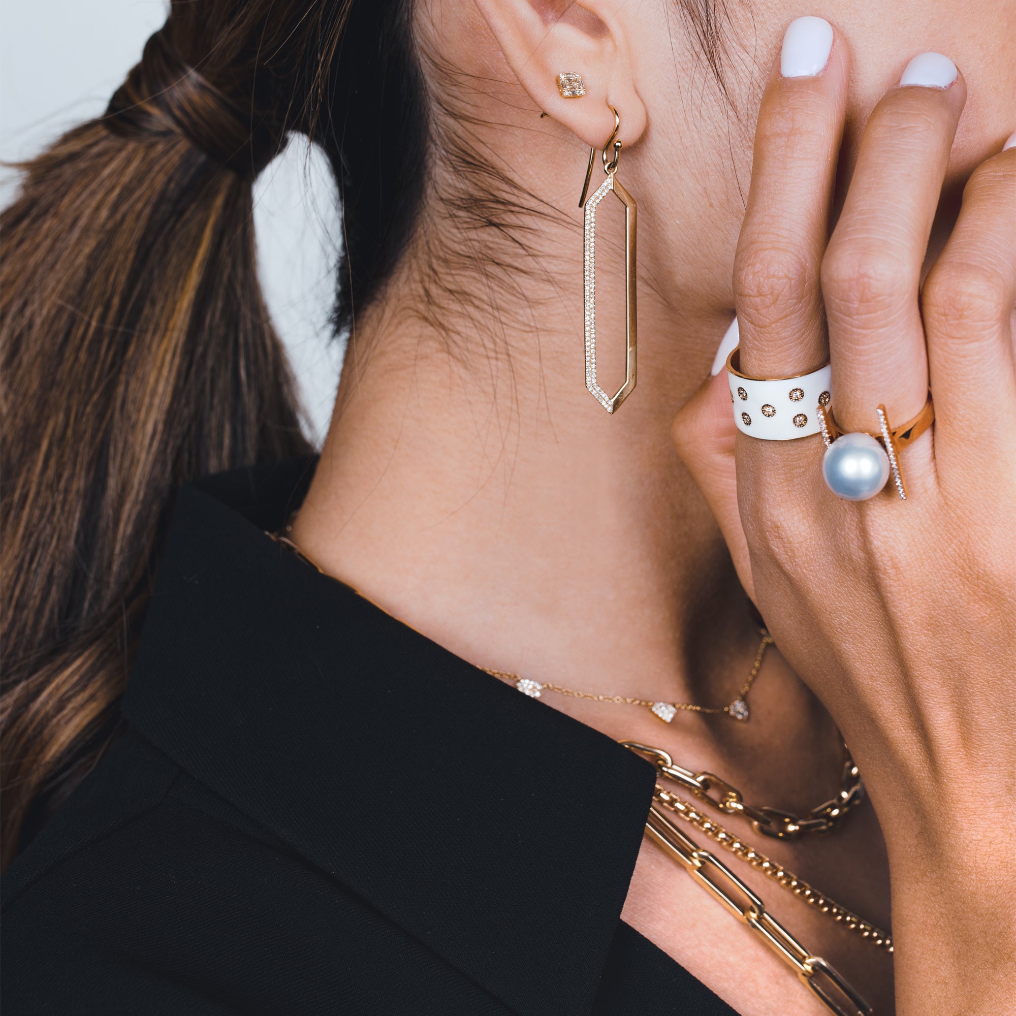 Side profile of woman wearing the Enamel Cigar Ring, thePearl with Diamond Bar Ring, and the Mirror Image Earring