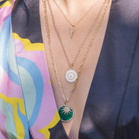 Woman is wearing the Enamel Target Necklace, the Mini Folded Heart Necklace, and the Starburst Diamond & Large Malachite Medallion Necklace