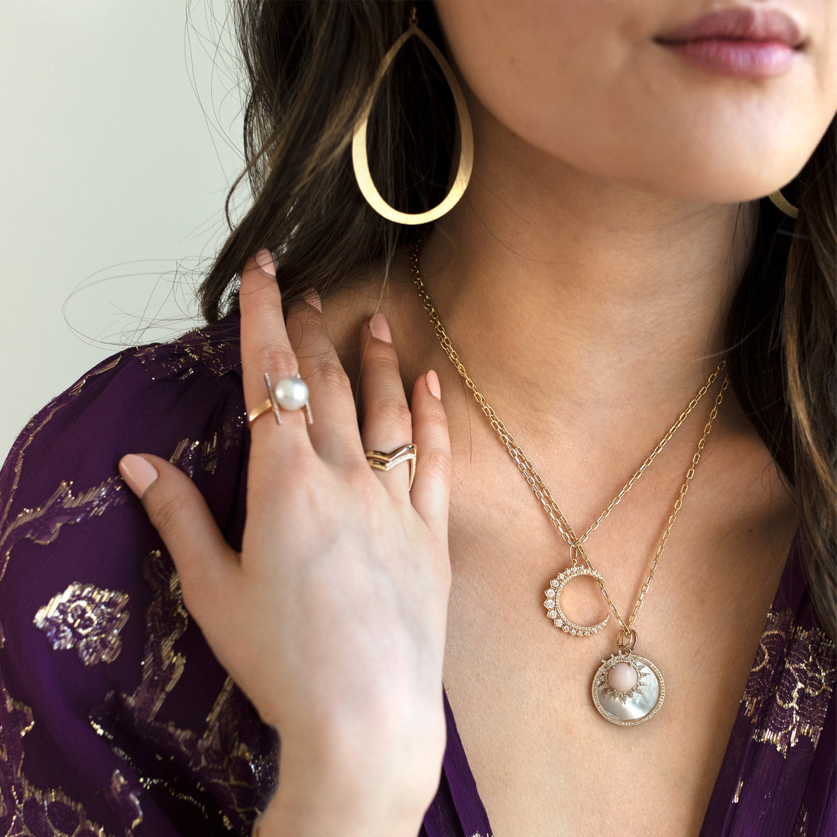 woman is wearing the Large Stackable Teardrops, the Large Diamond Crescent Necklace, the Pink Opal Sunrise and Large Mother-of-Pearl Medallion Necklace