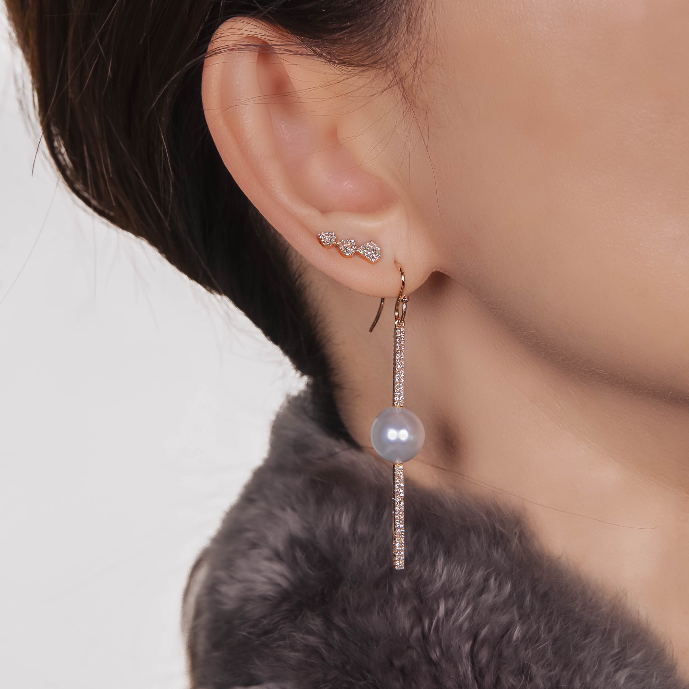 ear wearing the Reversible Diamond and Pearl Stick Earrings and the Triple Shield Studs