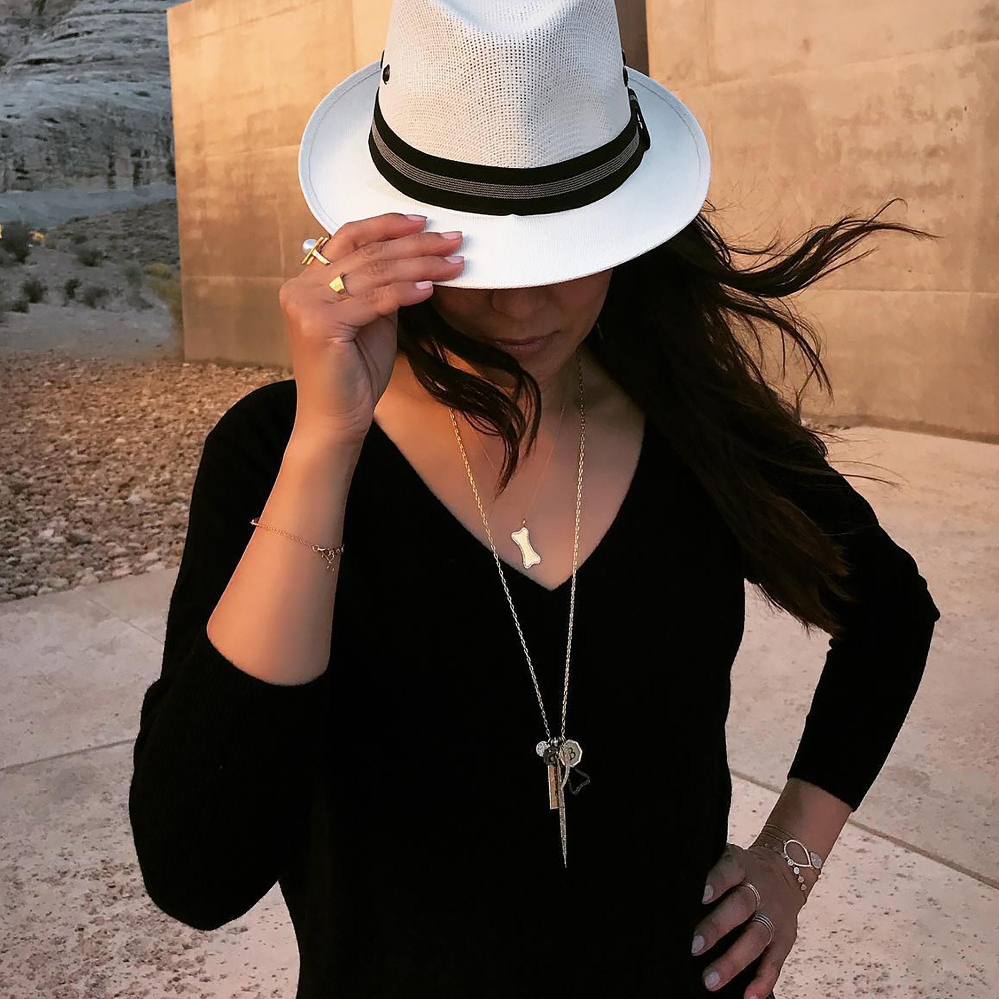 Woman is wearing the Small Diamond Dog Bone Necklace and a charm necklace