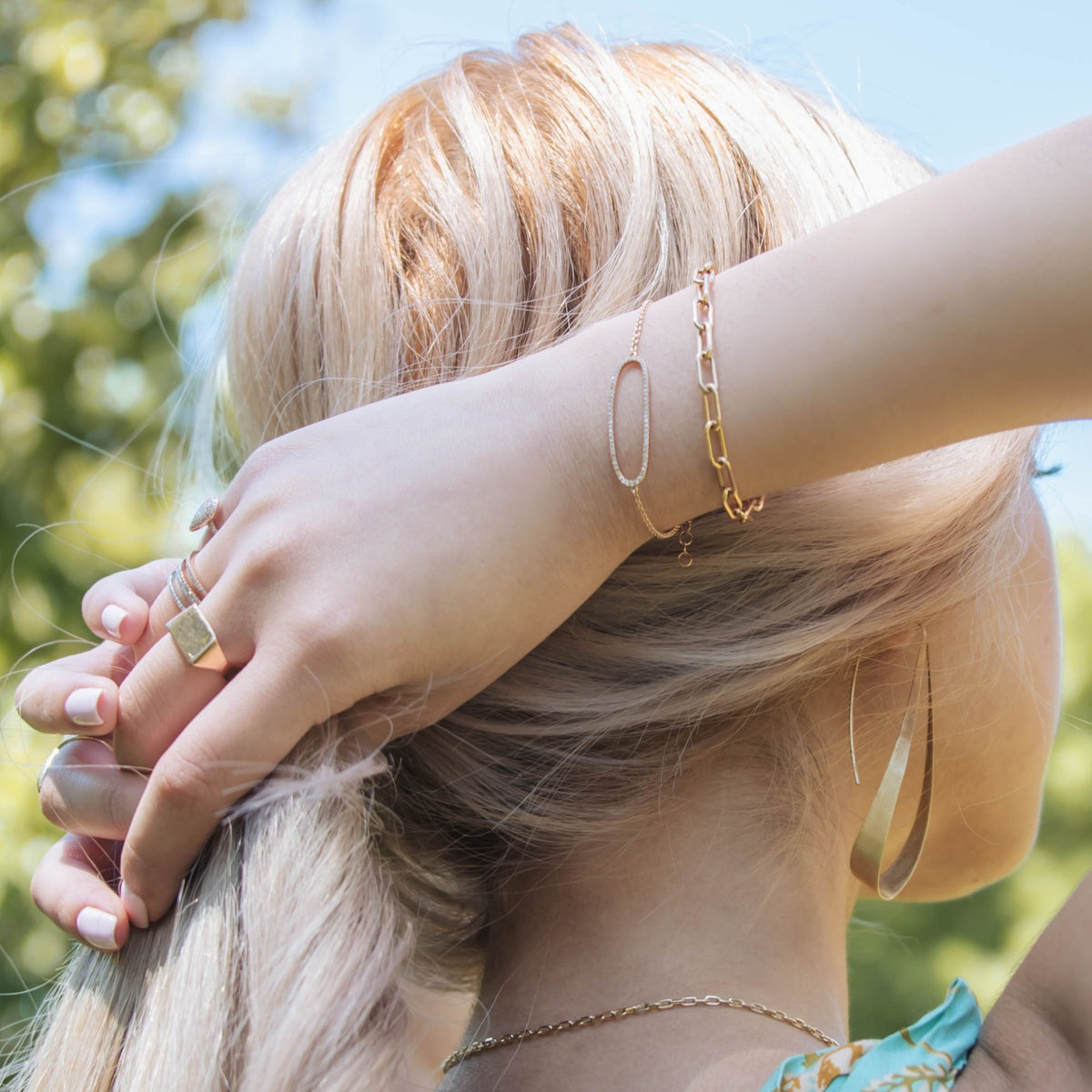 Woman wearing the Wing Earrings, the Diamond Oval Bracelet, and the Timeless Bracelet