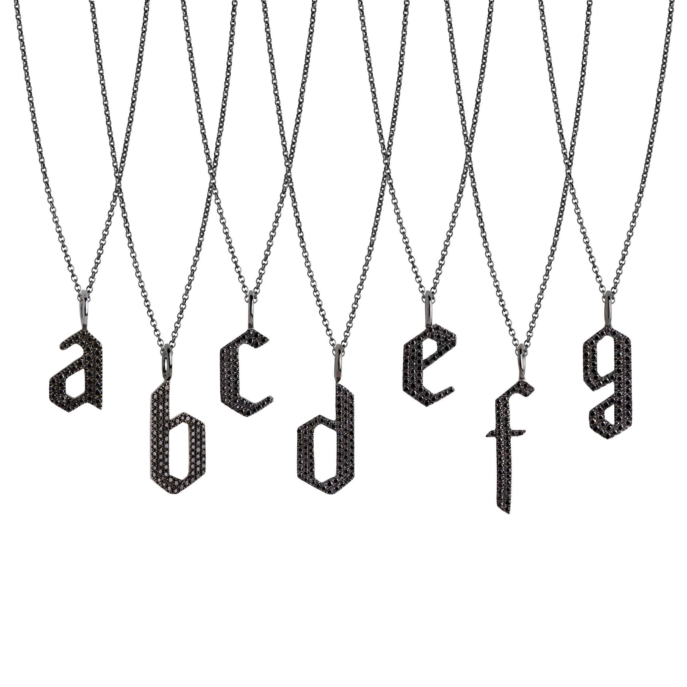 a - g Small Black Diamond Alphabet Necklaces: A series of oxidized sterling silver necklaces with black diamond letters, adjustable in length and featuring a lobster clasp fastening.
